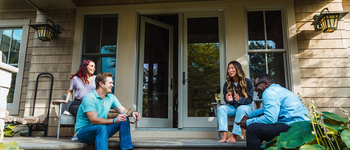 Four people sitting outside patio door on steps talking